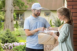 Courier holding a parcel and woman signing a delivery form photo