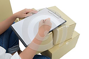 Courier making notes in delivery receipt among parcels on boxes
