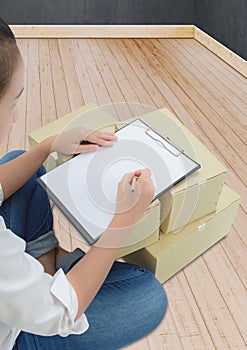 Courier making notes in delivery receipt among parcels on boxes