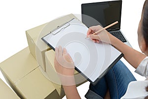 Courier making notes in delivery receipt among parcels on boxes