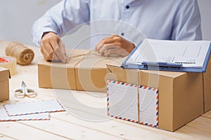 Courier making notes in delivery receipt among parcels at table