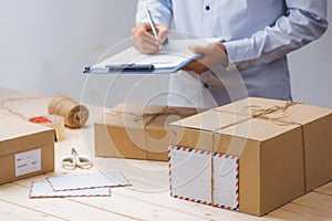 Courier making notes in delivery receipt among parcels at table