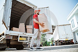 courier man in red uniform lifting parcel box from container