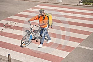 Courier man walking through the road with his bicycle