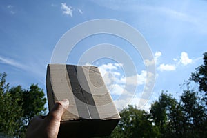 Courier package that has just arrived at the addressee as a gift held in hand against the sky photo