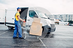 Courier with parcel trolley against logistic truck