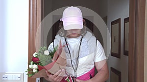 Courier in pink cap delivers fresh flower bouquet to client