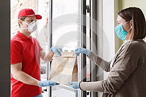 Courier in protective mask and gloves carefully gives package to client