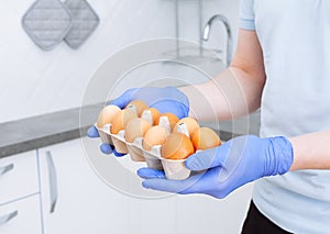 Courier in protective medical gloves delivers box with eggs stock for quarantine isolation period. Organic food and products