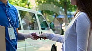 Courier receiving cash payment for cardboard parcel delivery, express shipping