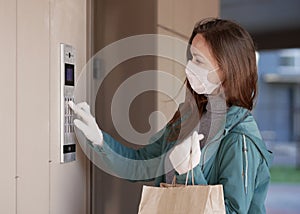 Courier`s hands in black medical gloves deliver parcels in paper bag to the door during the epidemic coronovirus, COVID