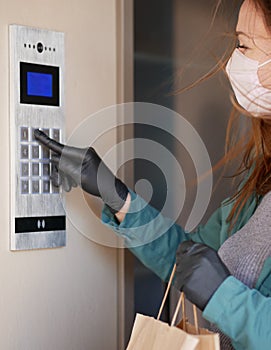 Courier`s hands in black medical gloves deliver parcels in paper bag to the door during the epidemic coronovirus, COVID