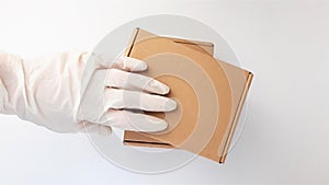 Courier`s hands in latex white medical gloves deliver parcels in brown cardboard boxes to the door during the epidemic of