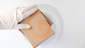 Courier`s hands in latex white medical gloves deliver parcels in brown cardboard boxes to the door during the epidemic of