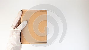 Courier`s hands in latex white medical gloves deliver parcels in brown cardboard boxes to the door during the epidemic of