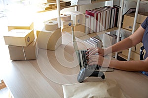 Courier scanning cardboard box with barcode scanner in warehouse. Close up of warehouse manager hand scanning boxes with barcode