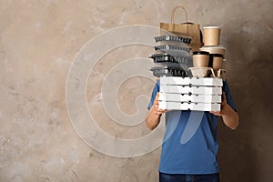 Courier with stack of orders on beige, space for text. Food delivery service
