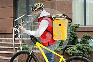 Courier with thermo bag, bicycle and mobile phone on street. Food delivery service