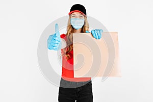Courier in uniform, with a medical mask on his face and gloves holding a paper bag with food on a white background. The concept of
