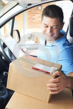 Courier In Van Delivering Package To Domestic House