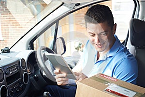 Courier In Van With Digital Tablet Delivering Package To House