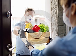 Courier or volunteer delivering shopping to woman during coronavirus quarantine. Woman customer receiving online order from