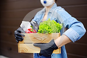 Courier or volunteer wearing medical face mask delivering shopping during coronavirus quarantine. Woman customer receiving online