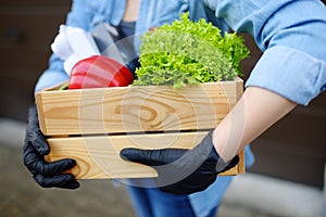 Courier or volunteer wearing medical face mask delivering shopping during coronavirus quarantine. Woman customer receiving online