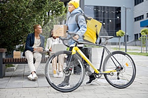 Courier walking with bicycle and business people