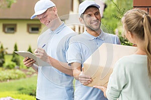 Couriers in blue uniforms and caps giving package to a customer