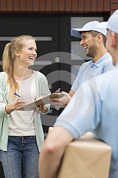 Couriers giving packages to happy customer signing receipt