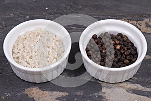Course gray salt and peppercorns in smal ramekins on gray slate