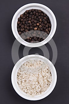 Course gray salt and peppercorns in smal ramekins on matte black