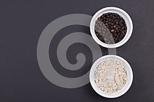 Course gray salt and peppercorns in small ramekins on matte black