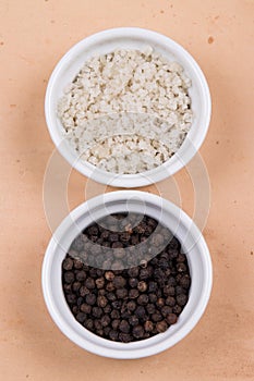 Course gray salt and peppercorns in small ramekins on saltillo ti