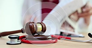 Court gavel with stethoscope on a table in background doctor writes notes