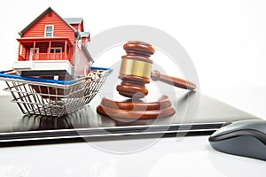 court hammer and auction on the background of a house model in a grocery basket and a laptop. legitimacy of real estate