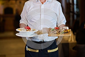 A courteous waiter provides impeccable service to an elderly family and their friends, creating a convivial atmosphere