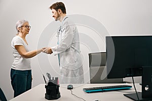 Courteous young doctor greets an elderly patient photo