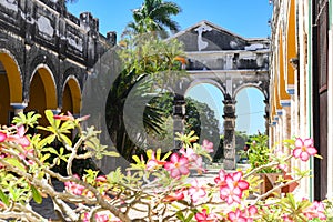 Hacienda courtyard with arches, palm trees and colorful flowers on a sunny day. photo
