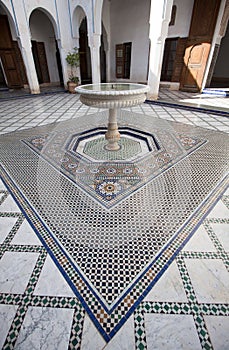 A courtyard with a fountain and mosaic tiled floor in a palace in Morocco