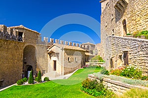 Courtyard with green grass lawn of Prima Torre Guaita first medieval tower with stone brick fortress wall, Republic San Marino