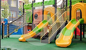 A courtyard of high-rise buildings with a new modern colorful and large playground on a rainy summer day without people. Empty