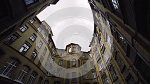 Courtyard of old round building in city. Action. Bottom view of old house with courtyard well on background of sky. Old