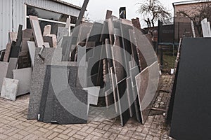 in the courtyard of a stonemason\'s workshop there are many different granite and marble slabs