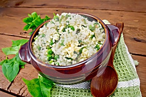 Couscous with spinach in bowl on board