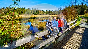 Cousins sitting on a bridge railing on the trails of Silverdale Creek Wetlands near Mission British Columbia, Canada