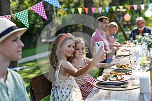 Cousins taking a selfie at a family garden party. Family reunion at garden barbecue party.