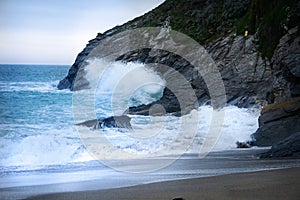 The cove with rushing waves against mountains near the Lusty Glaze Restaurant in Newquay, Cornwall, England.