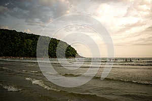 Cove with sunbathers and tourists on the beach on beautiful picturesque day with mountains